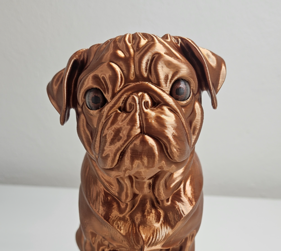 Close-up of a copper-toned pug statuette with carefully detailed eyes
